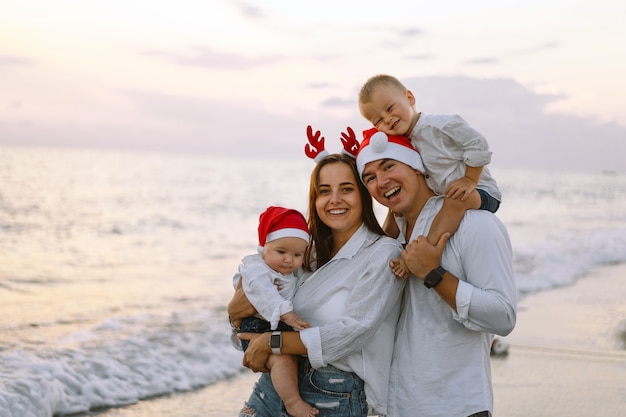 Photo family in a red santa hat walk on the beach family celebrate christmas and new year at tropics