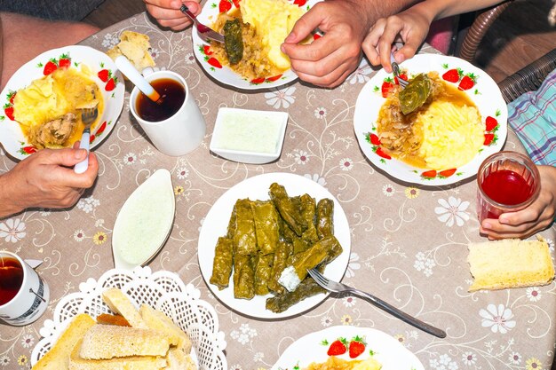 The family at the round table takes food top view Lunch dishes dolma with sauce mashed potatoes and cabbage