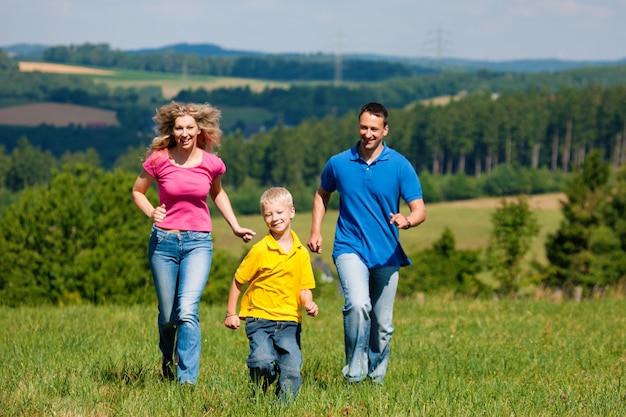 Family running on meadow in summer