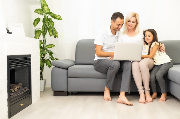 Acquisti in famiglia online. famiglia felice che sorride mentre è seduta sul divano e fa shopping online insieme