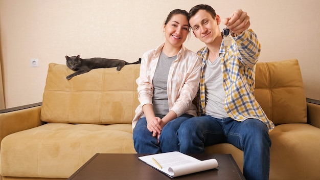 Family shows keys sitting with cute cat on sofa in room