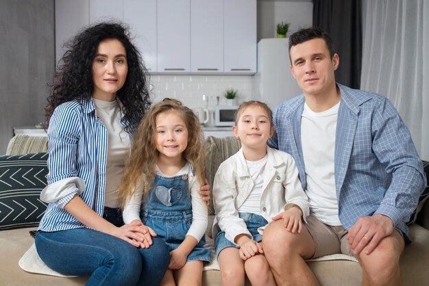 Photo family sits on sofa and demonstrates beautiful smiles