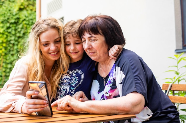 Family sitting closely watching smartphone together in cafe