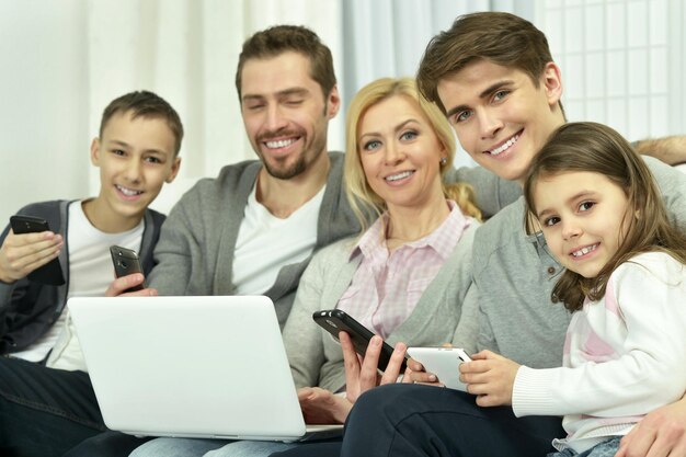 Family sitting on couch with laptop and other devices