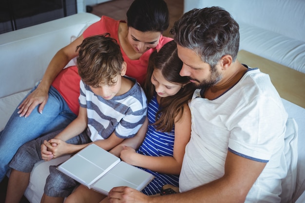 Family sitting on sofa and looking at a photo album