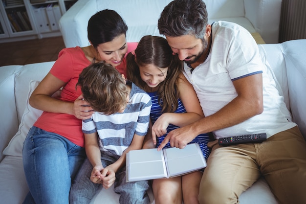 Photo family sitting on sofa and looking at a photo album