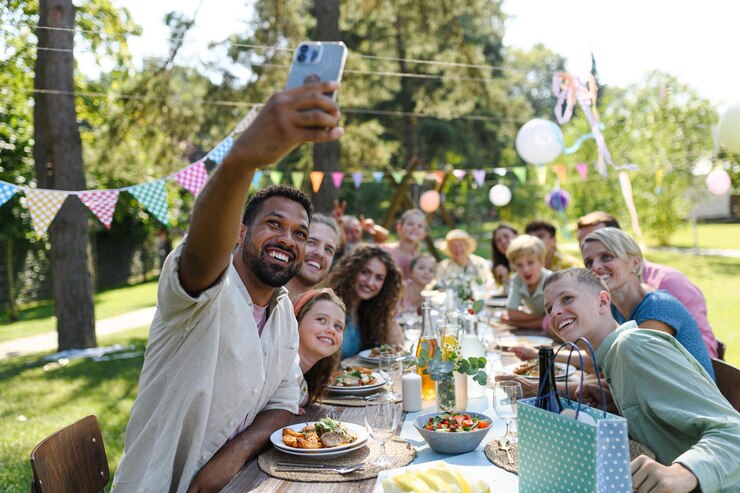 Photo family sitting at the table taking a group selfie at the family garden party