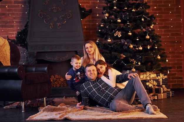 Family sitting together in christmas decorated room with New year tree.