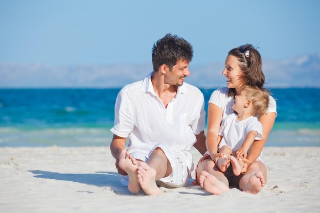 Foto famiglia seduta sulla spiaggia tropicale