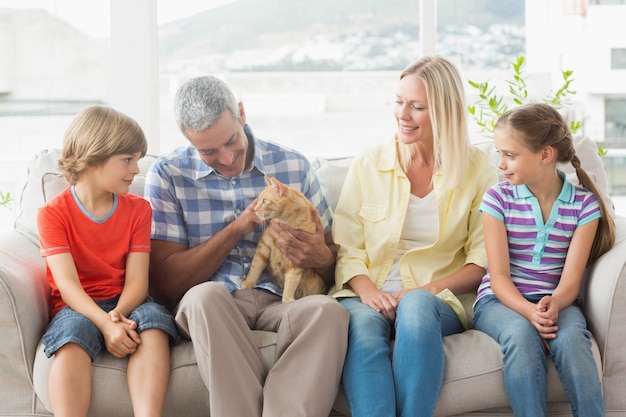 Family sitting with cat on sofa at home