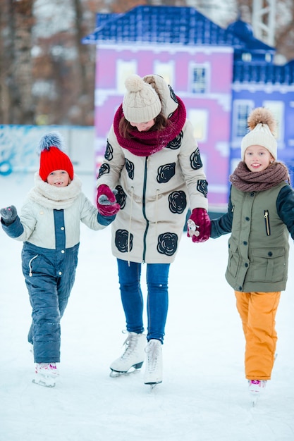 Family skating on ice-rink. Mother and kids learning to skate at winter