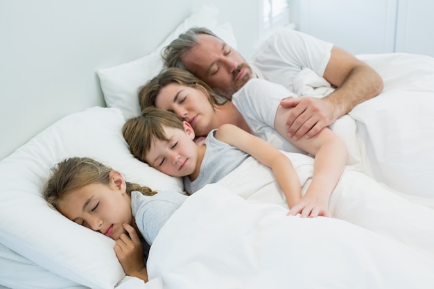 Photo family sleeping together in bed