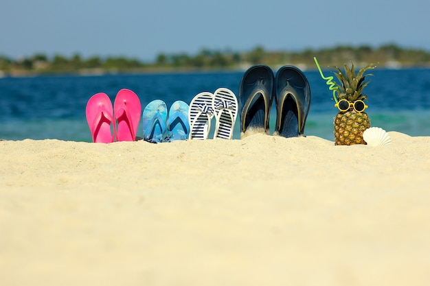 Pantofole per famiglie sulla sabbia in spiaggia in estate