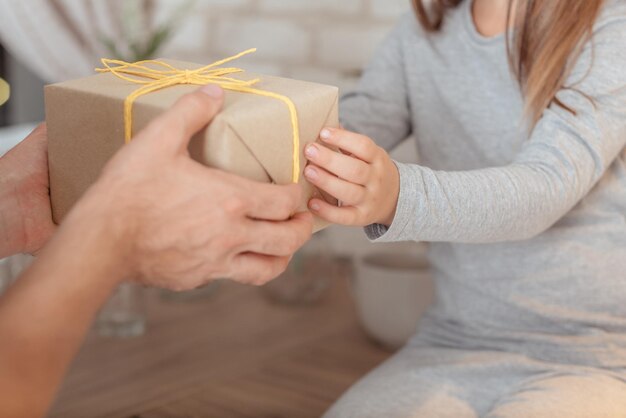 家族の特別な日家のお祝い愛情深い父親が幼い娘にサプライズプレゼントを贈るクロップドショット