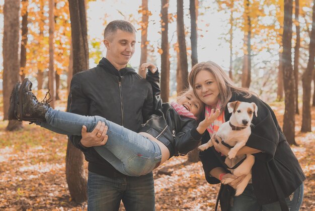 Family spend time in autumn park with a dog father mother and daughter and jack russell terrier dog