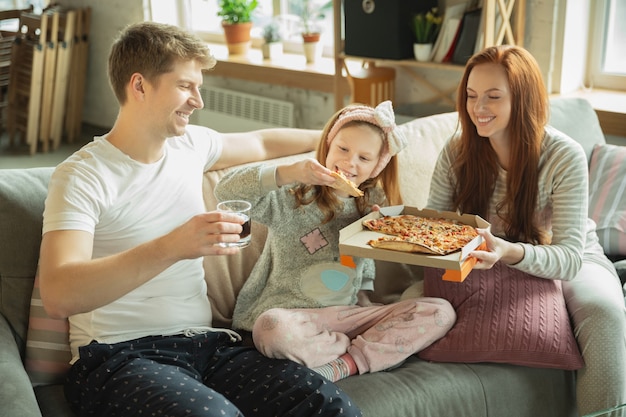 Фото Семья, проводящая время вместе дома, выглядит счастливой и веселой, ест пиццу
