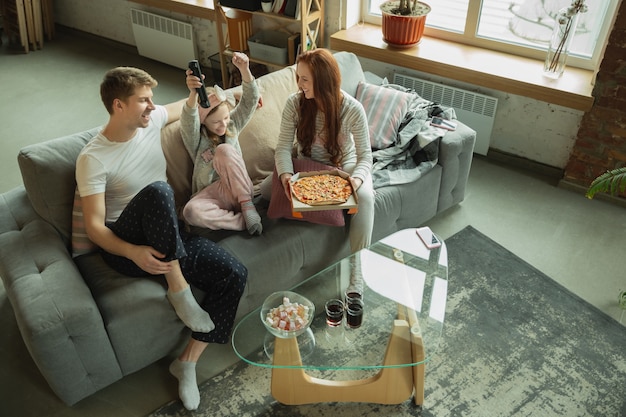 La famiglia che trascorre del tempo insieme a casa sembra felice e allegra mamma papà e figlia