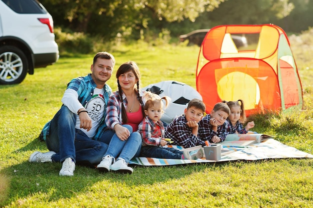 一緒に時間を過ごす家族 4 人の子供と両親が屋外でピクニック ブランケットを着ている 市松模様のシャツを着た大家族