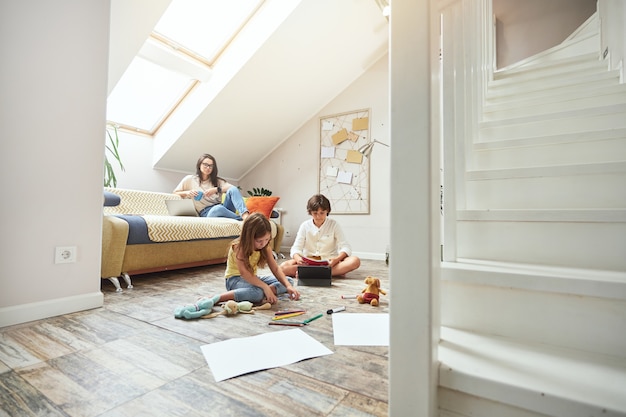 La famiglia trascorre del tempo insieme a casa i bambini seduti sul pavimento e giocando mentre la madre con