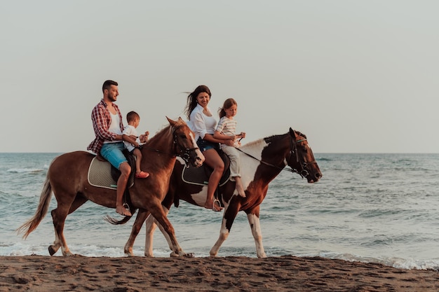 The family spends time with their children while riding horses together on a sandy beach. Selective focus. High quality photo