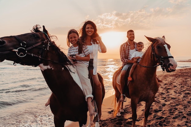 The family spends time with their children while riding horses together on a sandy beach. Selective focus. High quality photo