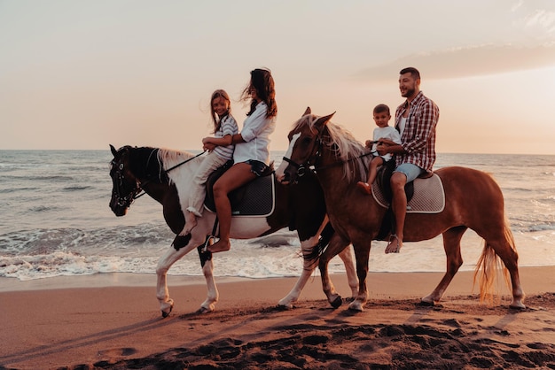 The family spends time with their children while riding horses together on a sandy beach. Selective focus. High quality photo