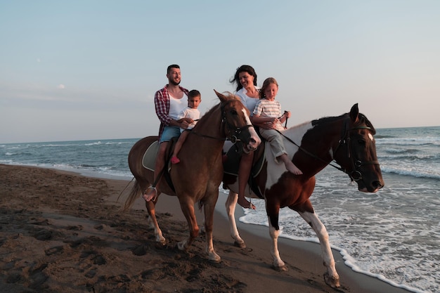 The family spends time with their children while riding horses together on a sandy beach. Selective focus. High quality photo