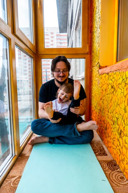 Family sport father teaches son to do exercises In a home apartment