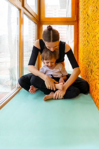 Family sport mother teaches son to do exercises In a home apartment