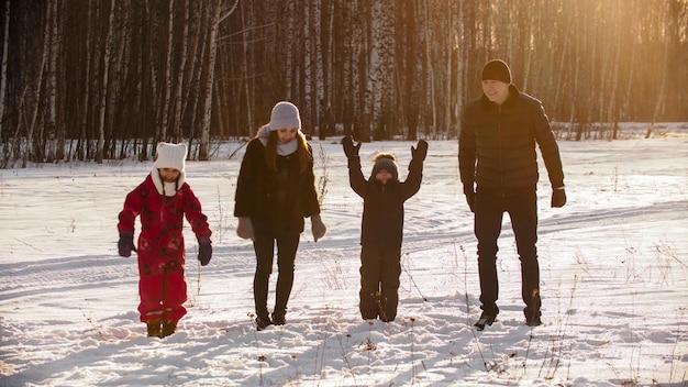 Family standing outdoors at winter and about to jump