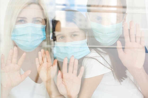 Family, standing behind the window, at home, quarantine due to coronavirus