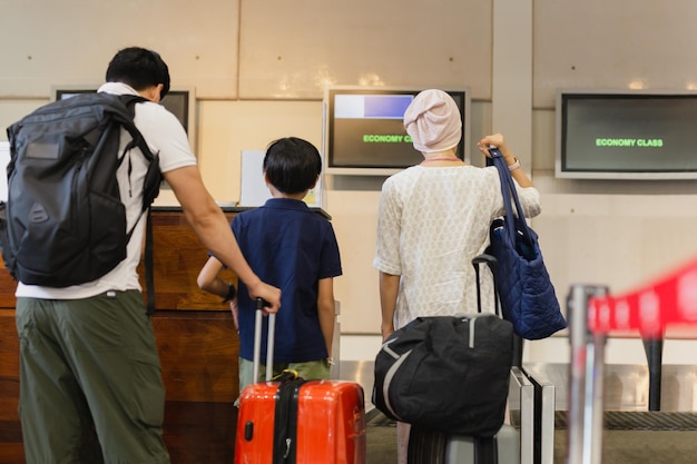 Famiglia in piedi con il check-in dei bagagli all'aeroporto