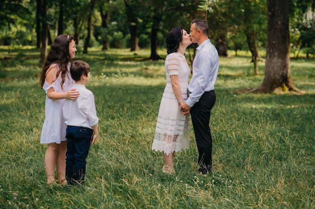 A family stands in a field and kiss their parents.