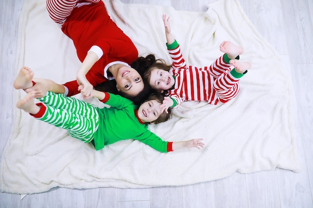 A family in striped pajamas is resting at home. Little children dressed as elves are lying on the sofa. A happy family.