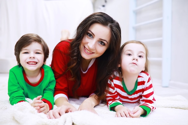 Una famiglia in pigiama a righe riposa a casa. i bambini vestiti da elfi sono sdraiati sul divano. una famiglia felice.