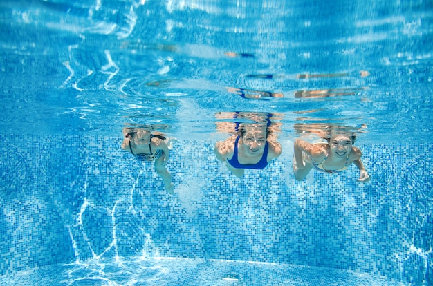 La famiglia nuota in piscina sott'acqua, felice madre attiva e bambini si divertono sott'acqua, fitness e sport con i bambini in vacanza estiva