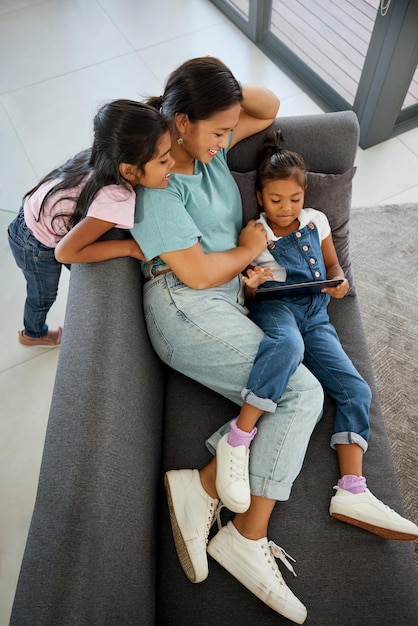 Family tablet sofa relax and mother on the internet with children happy with subscription service show on tech and happy with games on web in house Sisters watching video on technology with mom