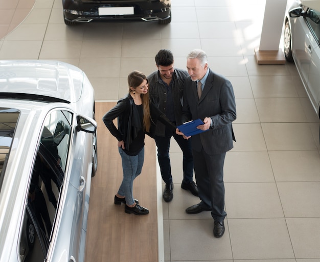 Family talking to the salesman and choosing their new car in a showroom