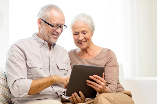 가족, 기술, 나이, 사람 개념 - 집에서 태블릿 PC를 사용하는 행복한 노부부