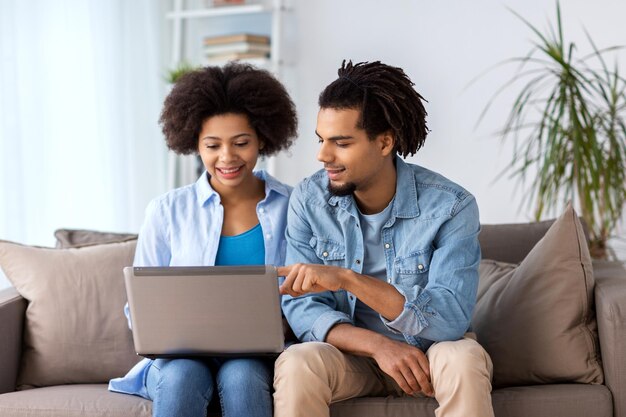 family, technology, internet and people concept - smiling happy couple with laptop computer at home