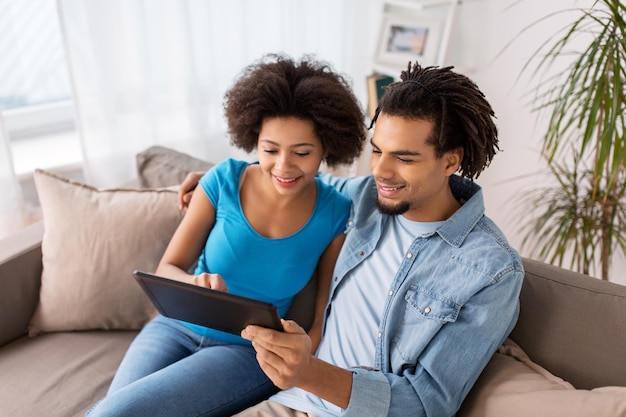 family, technology, internet and people concept - smiling happy couple with tablet pc computer at home