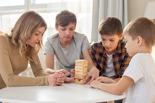 A family three boys and a woman are enthusiastically playing a board game