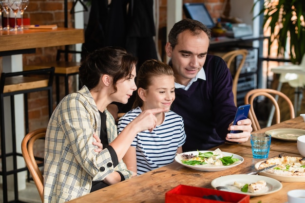 Family of three at a dining table taking a selfie