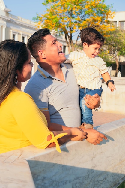 Foto famiglia di tre persone. il padre tiene in braccio suo figlio. il figlio guarda in basso. la madre sta guardando il bambino