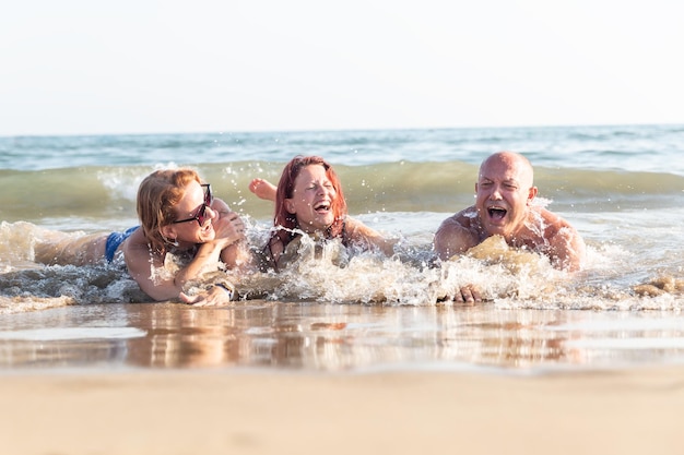 父母と娘の 3 人家族が浜辺に寝そべって共同休暇を楽しんでいる