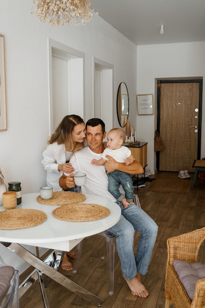 A family of three is having breakfast mom is standing drinking coffee dad and baby