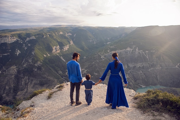 Family of three people stands on the mountain gorge during sunset in Dagestan