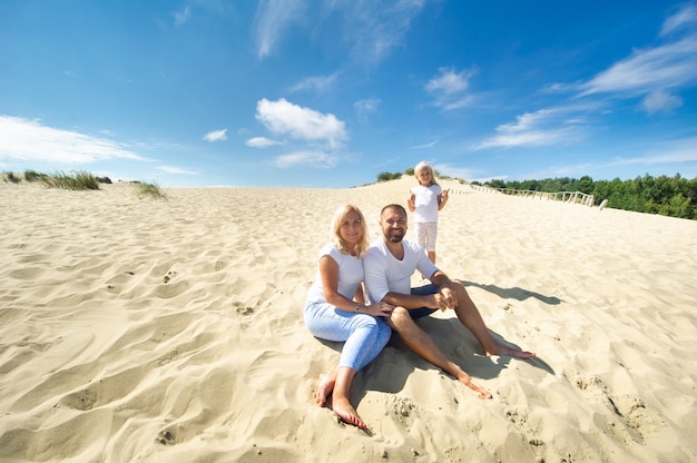 A family of three sit on the sand dunes near the town of Nida.Lithuania