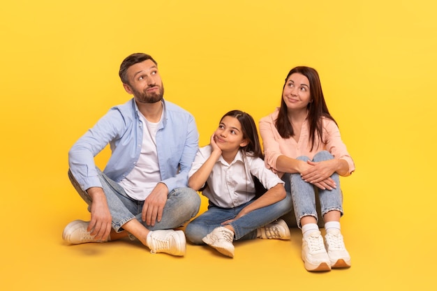 Photo family of three sitting together with pensive expressions thinking studio