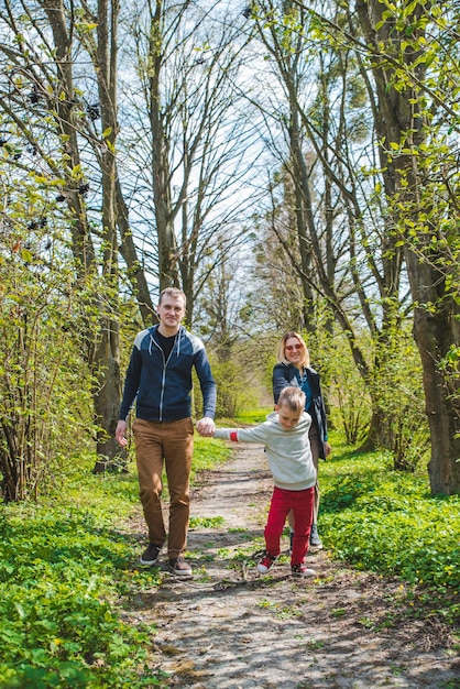 Family of three walking by park trail in sunny day happy kid